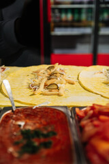 Hands rolling a shawarma wrap with fresh ingredients inside. Close-up of the food preparation process in a kitchen