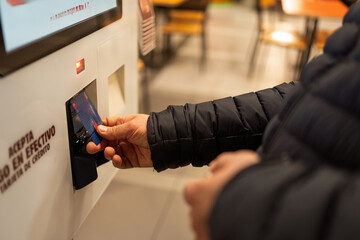 Person inserting credit card into self-service payment terminal