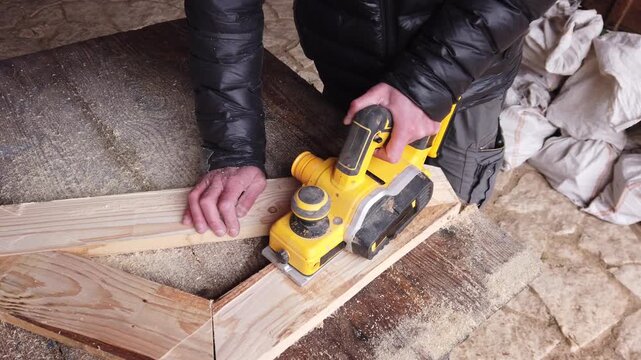 Hands of carpenter working with cordless brushless planer smoothing wooden board