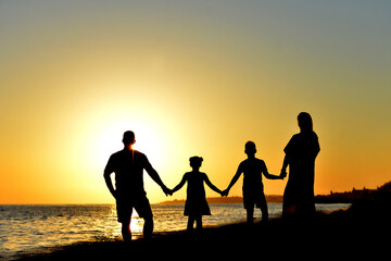 Obraz premium A Beautiful Family Silhouette at Sunset by the Sparkling Ocean
