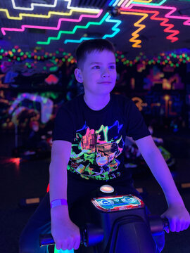 Boy playing video game in neon lit arcade
