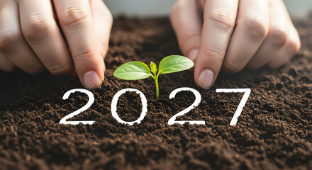 2027 on soil with plant sprout and protective hands — future eco growth theme