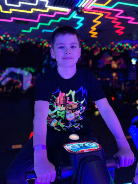 Boy playing arcade game under neon lights