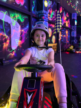 Smiling girl enjoying racing game in arcade