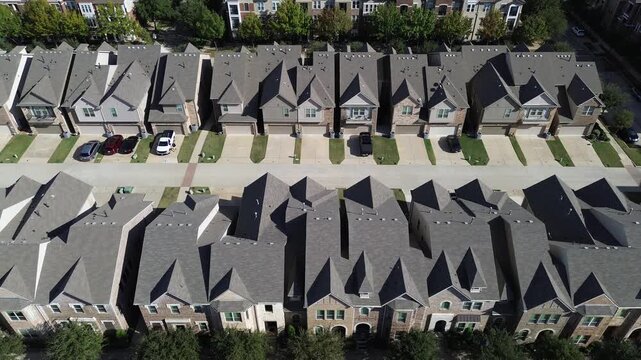 Uniform two-story townhouses in Flower Mound, Texas, arranged on narrow lots with pitched roofs, brick facades, driveways, and small lawns. Dense layout emphasizes suburban planning precision