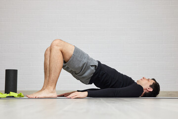 Man doing glute bridge on a mat indoors for fitness and strength training