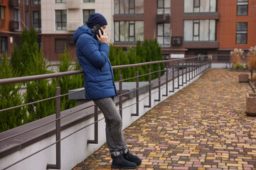 Man talking on mobile phone while leaning on railing in urban setting