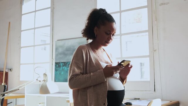 Pregnant black businesswoman using smartphone in office