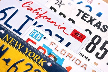 Old US car license plates with various state names close up. Concept of driving in United States. Reaching a car registration