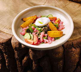 Fresh salad with poached egg and vegetables served on wooden background