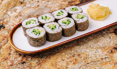 Fresh cucumber sushi rolls served on a white plate with ginger