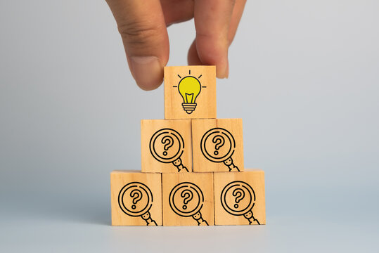 Solution, problem solving concept. Wooden blocks with a lightbulb and question mark magnifiers icons, symbolizing inquiry leading to insight and problem solving.