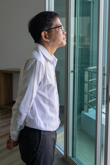 Asian businessman thinking, planning, finding a good solution or idea, looking outside through office building window