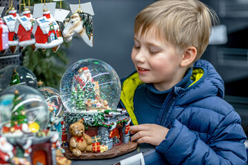 Boy Looking at Glass Christmas Snow Globe in Store