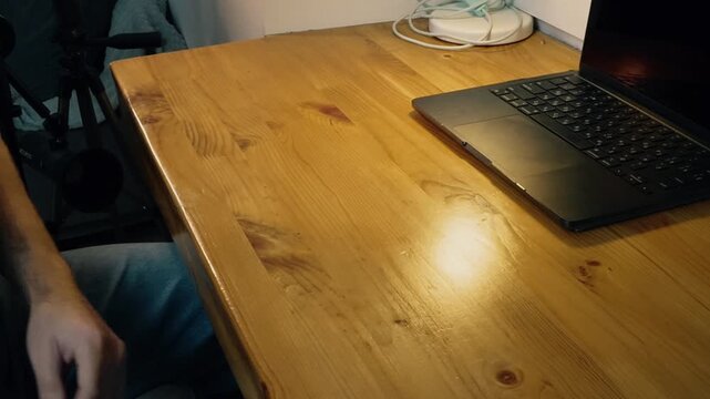 Close-up hands angrily sweeping stack of papers off wooden desk frustration stress failure loss of control evening warm lamp light laptop on table home office moment