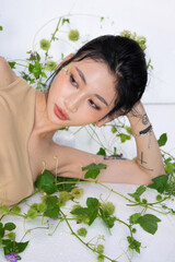 Overhead shot of the woman lying amidst plants, one arm bent behind her head.