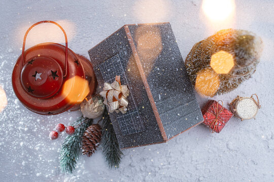 Miniature Christmas house with solar panels on the roof, glowing red lantern and snowy festive decorations. Cozy winter holiday scene for seasonal designs, New Year and Christmas.