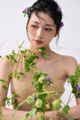 The woman adorned with vines and flowers, posing gracefully against a neutral background.