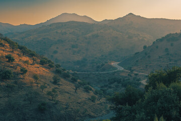 Hazy valley with hills and olive trees during sunset. Almogia, Malaga, Andalucia, Spain.