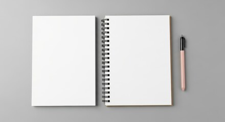 Open spiral notebook with blank pages and a pen on a gray surface.