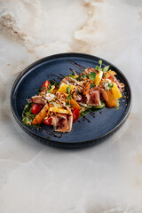 Fresh salad topped with thinly sliced prosciutto, colorful vegetables, and a dark balsamic glaze drizzle, highlighting vibrant textures, savory flavors, and an elegant gourmet presentation.