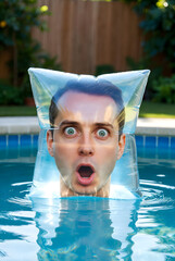 Surprised Man&rsquo;s Face Inside Inflatable Pillow Floating in Pool