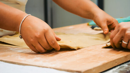 Child's hands preparing dough on a wooden board, carefully shaping homemade pastry, learning traditional baking skills in a hands on kitchen workshop