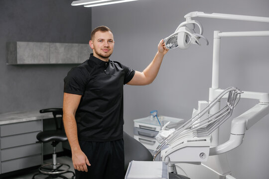 Male dentist adjusting dental light in modern clinic - Powered by Adobe