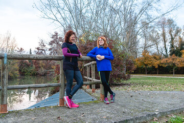 Women friends talking in autumn park after running