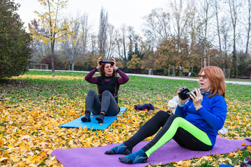 Women exercising with dumbbells doing sit-ups in park