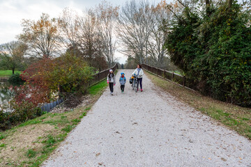 Family walking gravel path bridge during autumn season
