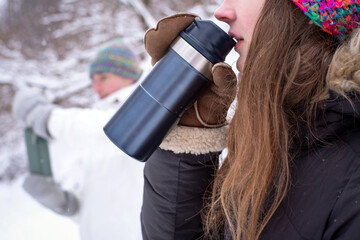 Naklejka premium Traveler woman enjoying hot coffee in snow, winter landscape, thermos cup, outdoor lifestyle moment