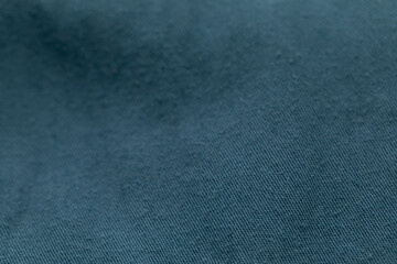 Closeup texture of soft, dark teal cotton fabric. The shallow depth of field highlights the woven...