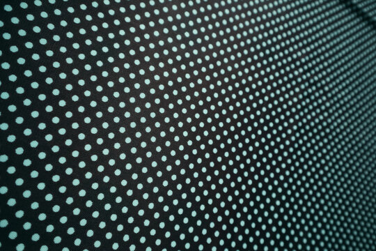 Black textile with a regular turquoise polka dot pattern.