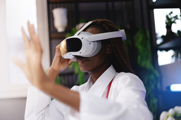 Portrait happy African female doctor using virtual reality headset in medical innovation concept, gesture with finger to press button, sunlight
