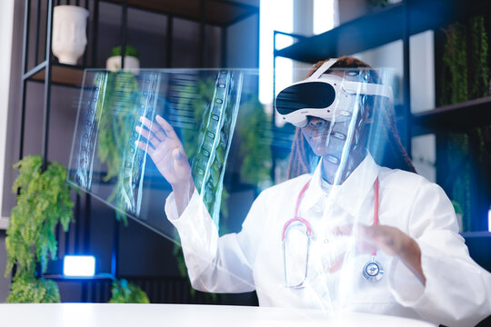 African female doctor uses virtual reality goggles for medical imaging mri scan of spinal in modern office