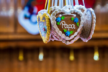 Gingerbread hert cookie decorated with floral details and the word Papa. Lebkuchenherz hanging at a german christmas market stall. Sentimental gift for occasions like father’s day, family celebrations