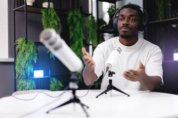Young african male podcaster wearing headphones discussing in studio