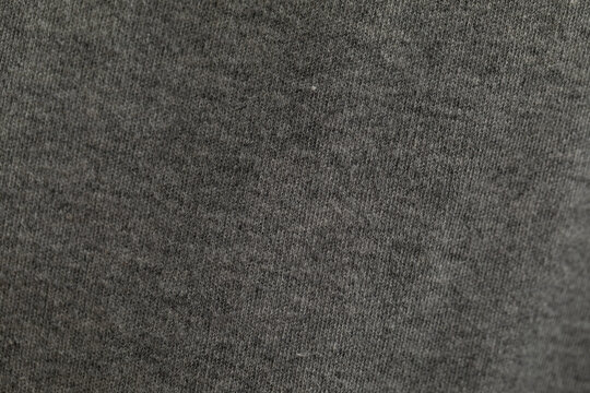 Close-up of a dark grey melange jersey fabric. The detailed texture of the knitted material makes an ideal abstract background or textile concept.