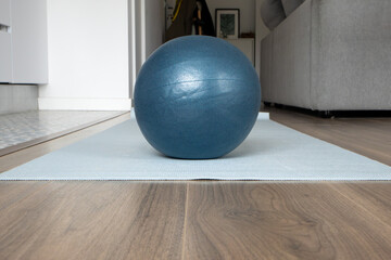 Pilates ball on yoga mat in modern living room. Home workout, wellness, mindful, exercising at home, yoga practice, healthy lifestyle