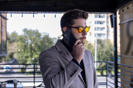 A man is talking on his phone on a balcony