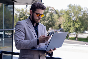 A man in a suit and sunglasses intensely focused on using a laptop