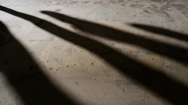 Concrete floor with a rough patch and shadows in a well-lit industrial space showcasing gradual changes in light and texture throughout the footage.