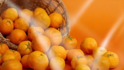 Close-up of fresh oranges spilling from a woven basket onto a vibrant orange background with soft natural light highlighting their textures and colors showcasing the bright juicy fruit in a studio - Powered by Adobe