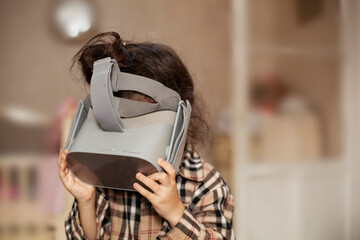 Future education concept. Toddler looking through VR goggles exploring metaverse or cyberspace