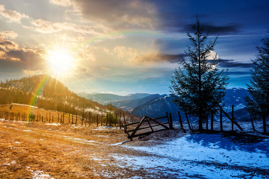 countryside mountain landscape on spring equinox. day and night time change concept. spruce trees and fence on meadow with snow under sun and moon. snowy distant ridge. duality and transition template - Powered by Adobe