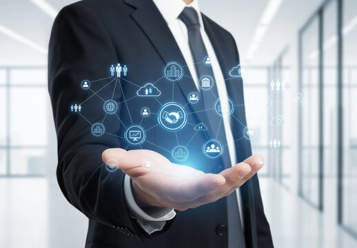 Businessman's hand holds illuminated connected business icons with modern office background. Suitable for web design, marketing materials, presentations. 