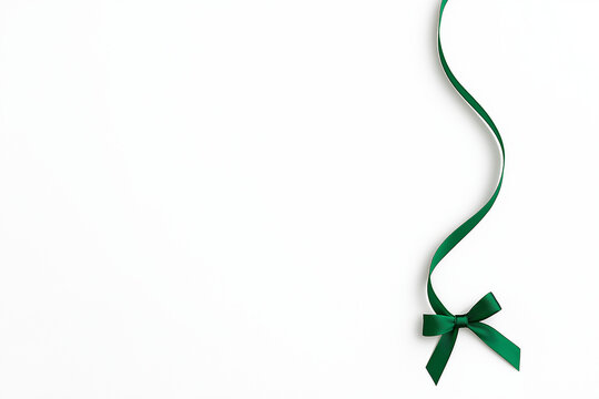 Green ribbon with a bow on a white background, perfect for holiday designs, gift wrapping, invitations, and festive decorations.