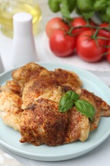 Tasty roasted chicken thighs with basil served on white table, closeup