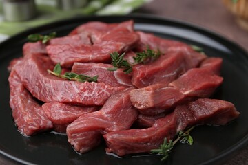 Pieces of raw beef meat and thyme on table, closeup